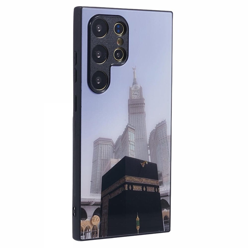 A smartphone with a protective case featuring an image of the Kaaba at the center, with the Abraj Al Bait clock tower in the background, both located in Mecca, Saudi Arabia. 